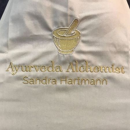 Logoservice - "Ayurveda Alchemist Sandra Hartmann"-Aufnäher, auf einer Schürze